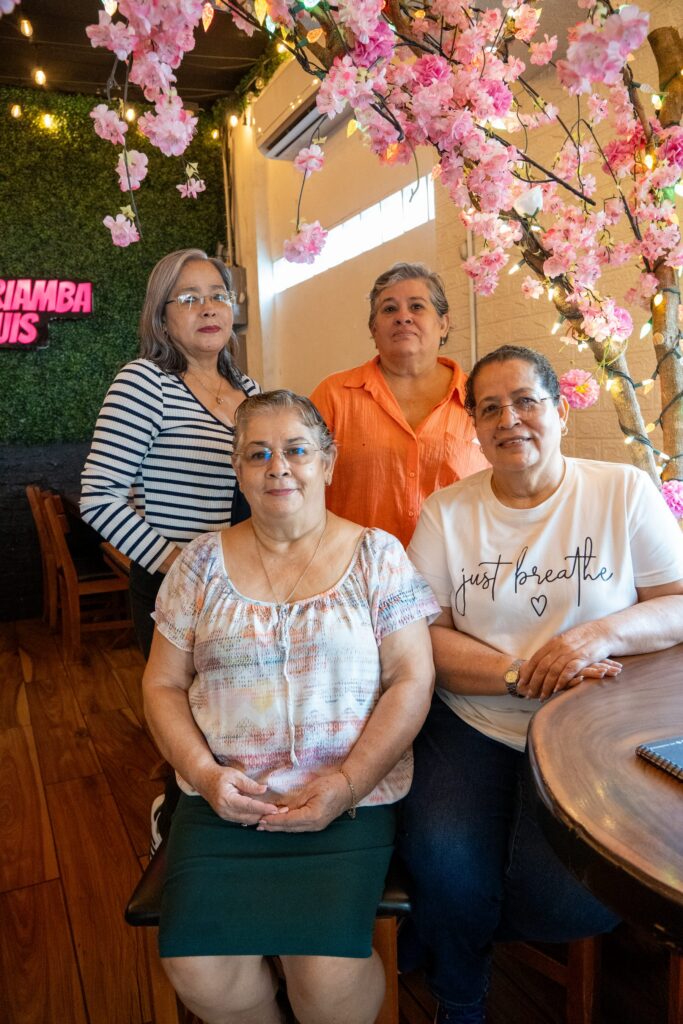 Las fundadoras de RiQUi's en el local de Diriamba, bajo el árbol de flores de cerezo y el rótulo de neón